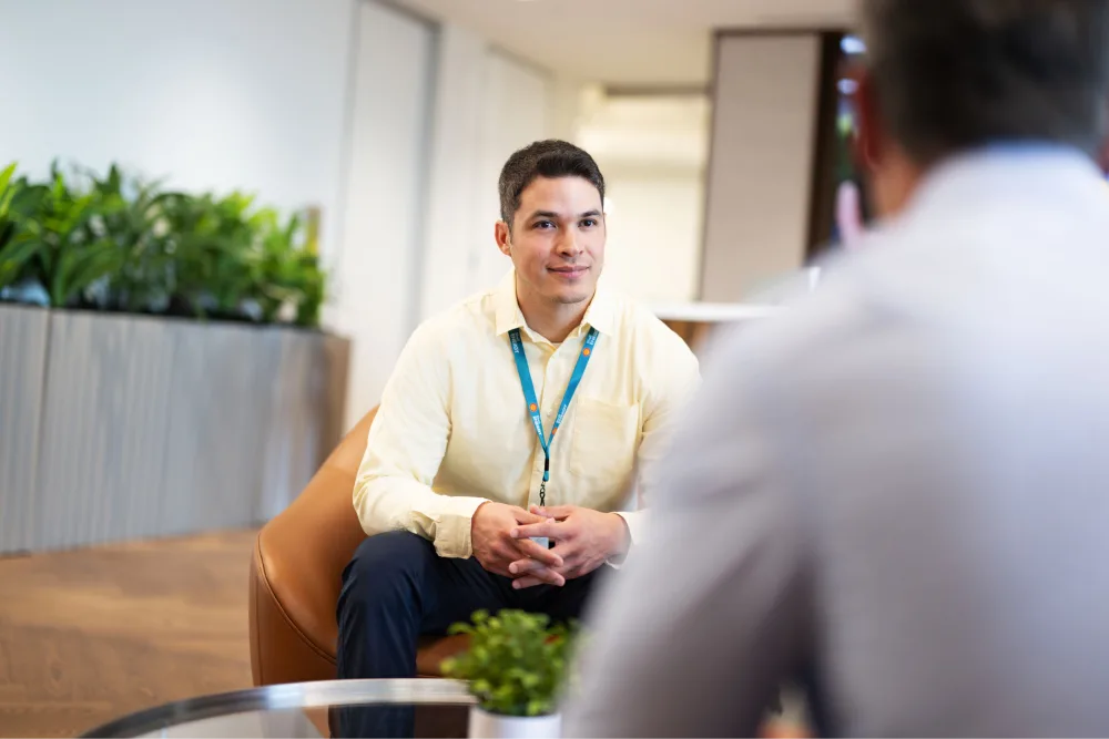 A Shell employee seated in a modern office lounge, attentively listening to a colleague during a conversation