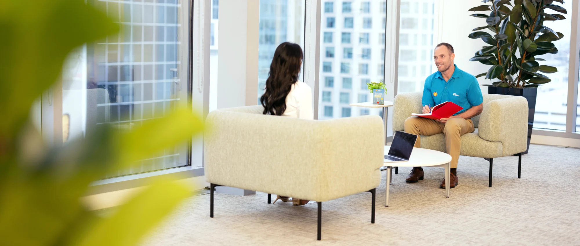 Shell employee and woman sitting down and talking at an office space